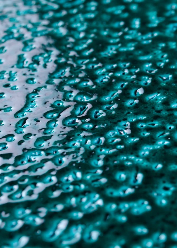 Close-up of glazed lava stone surface — teal glaze fused to volcanic stone by Ranieri